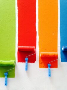 Different colored paint rollers on a wall.