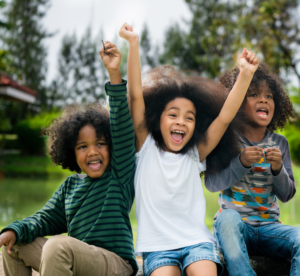 Three kids sitting outside cheering--cambio c