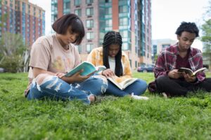 Tres niños leyendo libros afuera--Three kids reading books outside--entorno construido