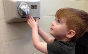 Young boy uses a hand dryer after washing his hands---drying hands