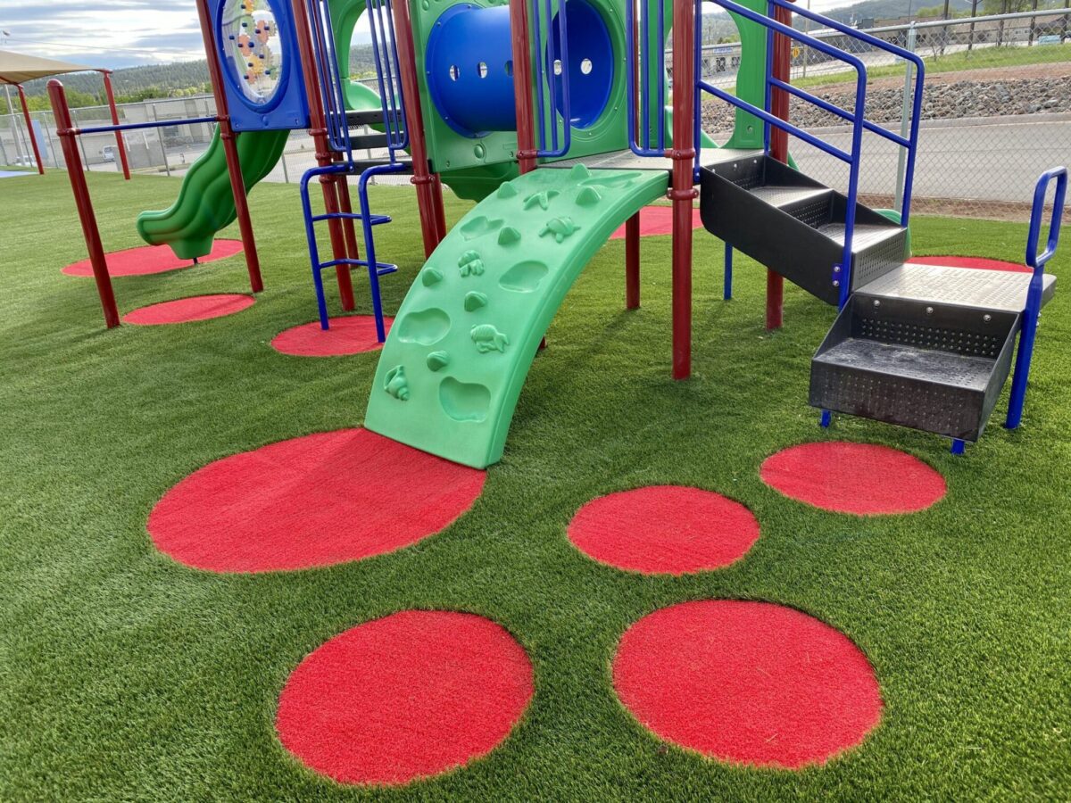 A small playground with red and green turf--Césped Artificial