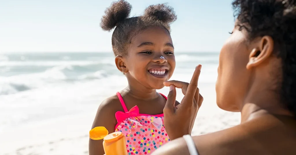 A mother is putting sunscreen on her young daughter at the beach--Sunscreen