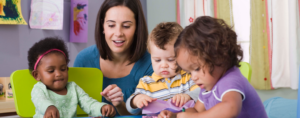 Woman interacting with three young children at a classroom table