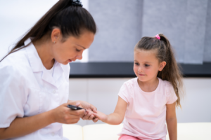 A girl getting her finger pricked at the doctor's office