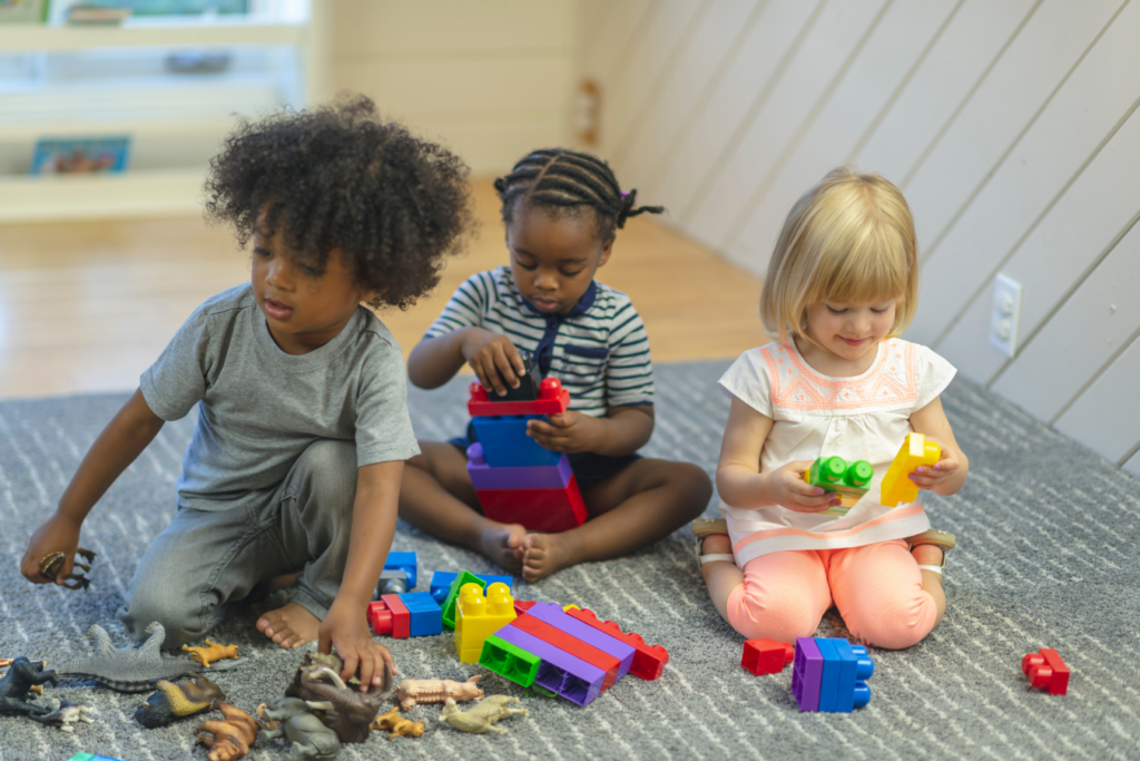 Three kids playing with toys on a carpet