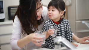 Mother and daughter drink tap water out of glasses in a kitchen Denver Water's Lead Reduction Program