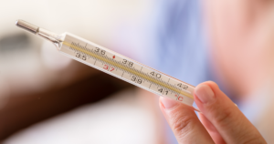 Closeup of a hand holding a mercury thermometer