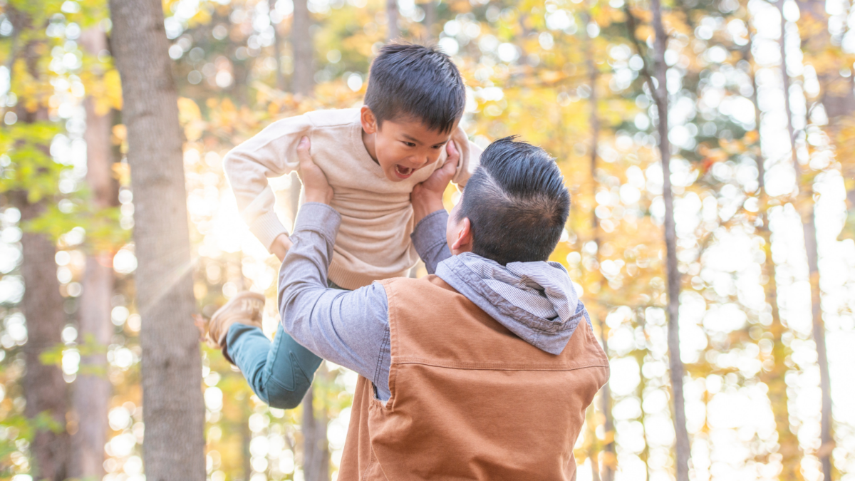 Adult holding child in a sunny forest--Connecticut children's environmental health