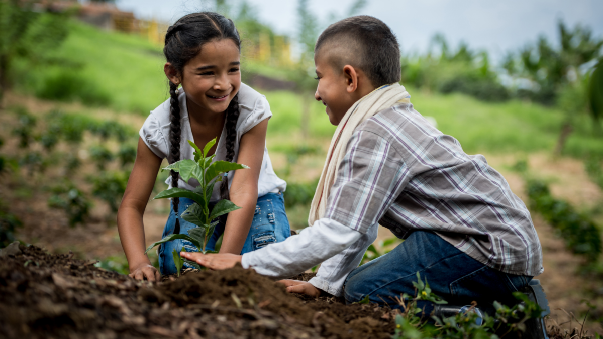 Two children sitting down tending to a plant - Georgia children's environmental health