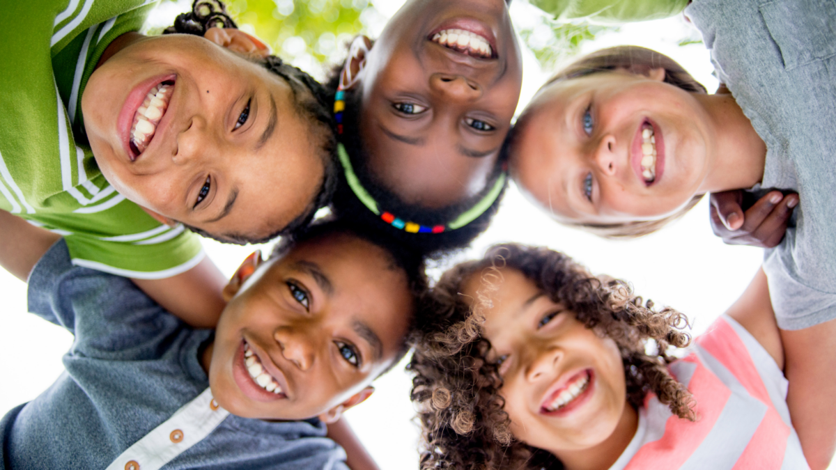 Five children in a circle leaning in over a camera and smiling - Louisiana children's environmental health