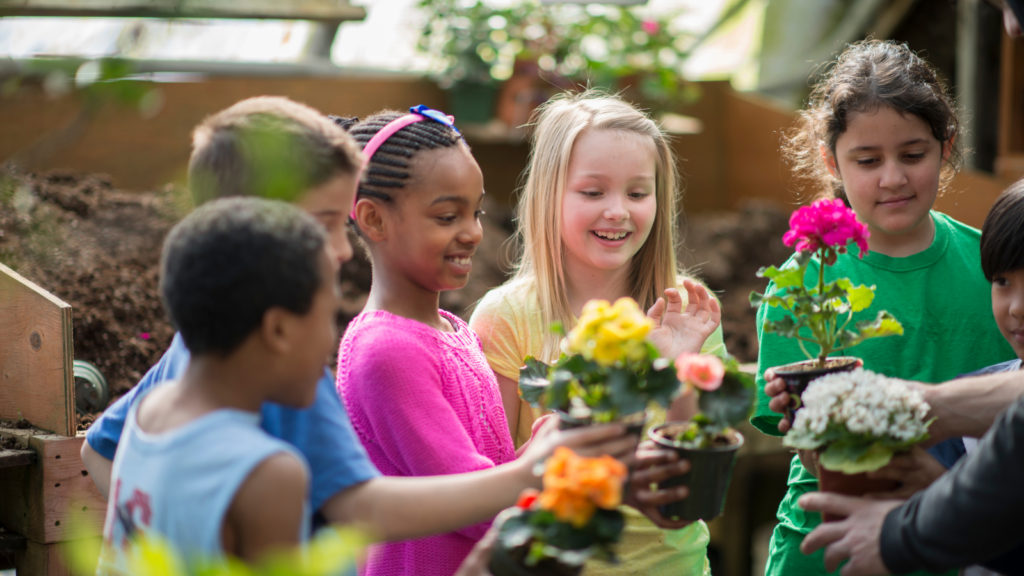 Children standing in a group holding potted plants - Maine children's environmental health
