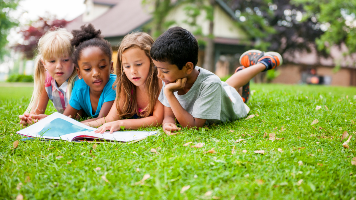 Children laying on the grass reading a book - Mississippi children's environmental health