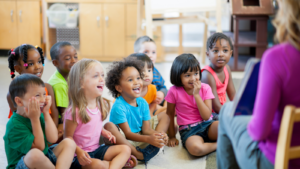 Children sitting on the floor watching their teacher read a book - Missouri children's environmental health