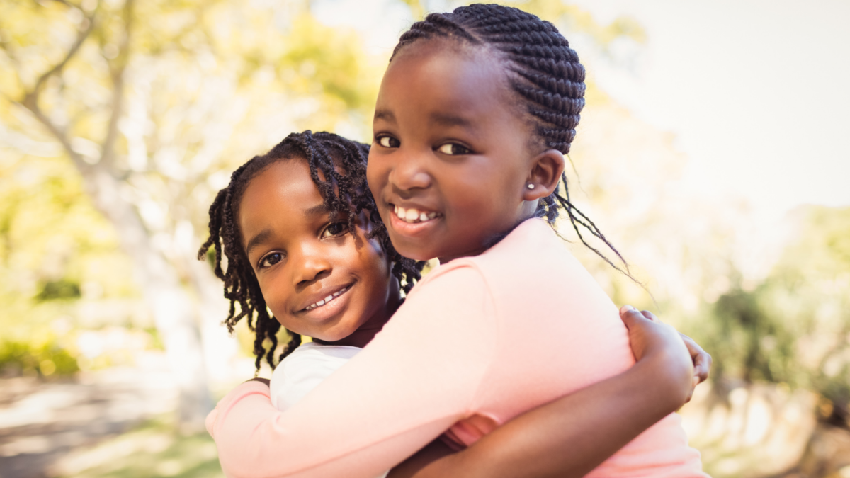 Two children hugging and smiling at the camera - North Dakota children's environmental health