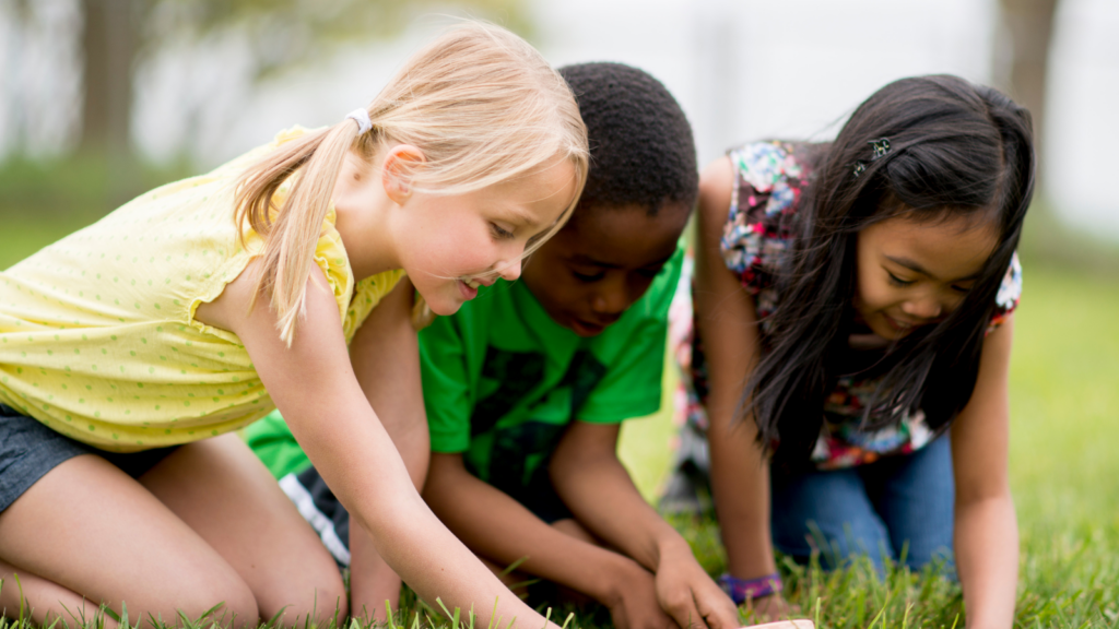 Three children kneeling down in grass -- Tennessee children's environmental health